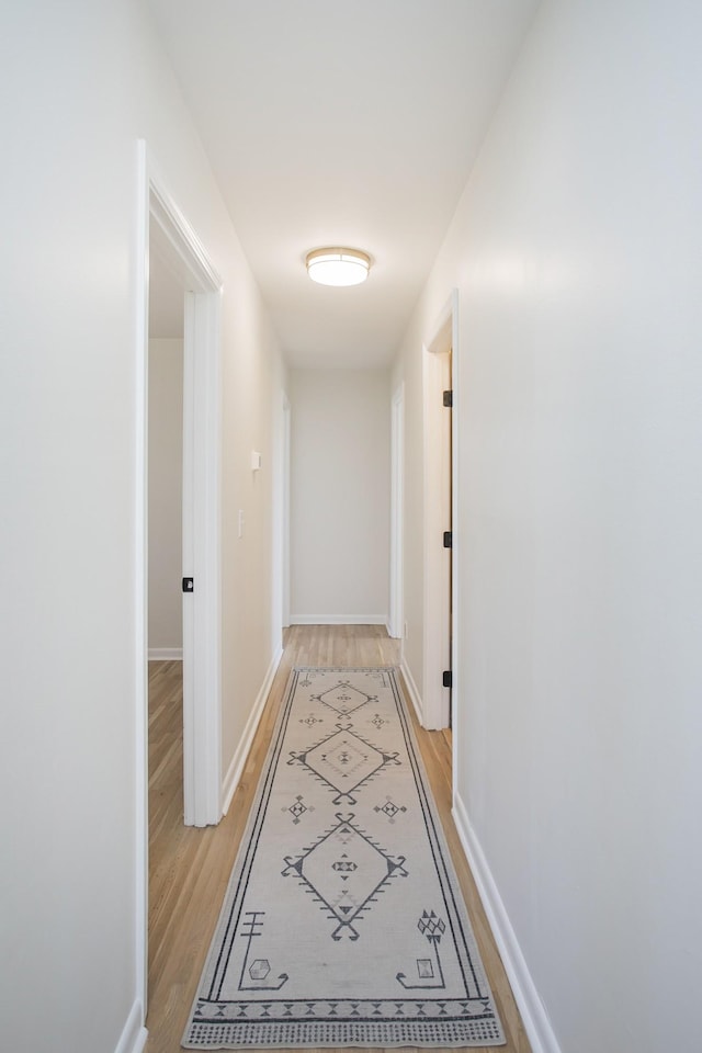 hall with baseboards and light wood-style floors