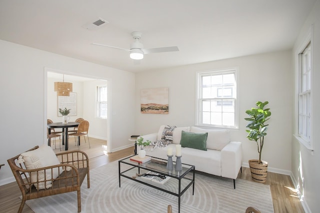 living area with wood finished floors, visible vents, and baseboards