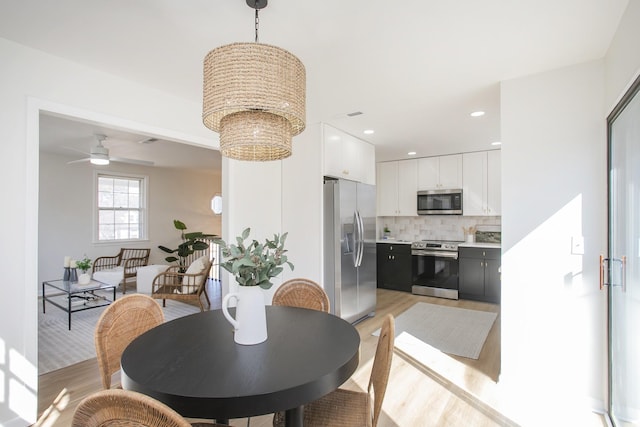 dining area with ceiling fan with notable chandelier, light wood finished floors, and recessed lighting