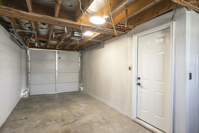 garage featuring concrete block wall and a garage door opener