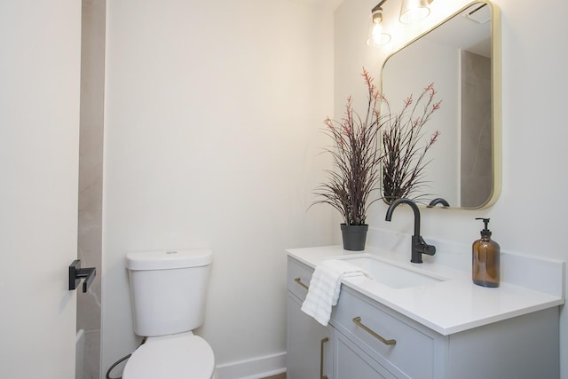 bathroom featuring baseboards, vanity, and toilet