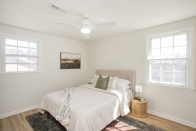 bedroom featuring baseboards, visible vents, and wood finished floors