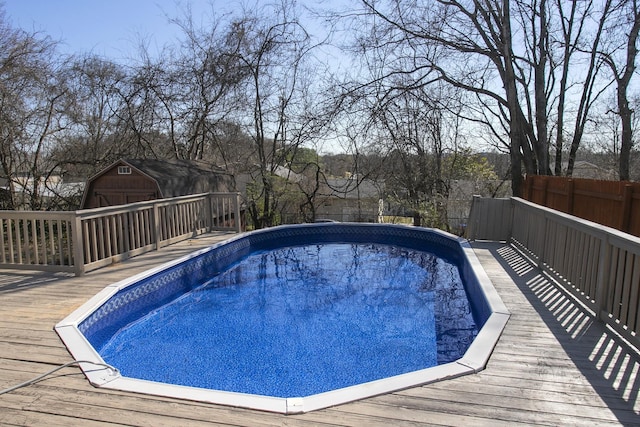 outdoor pool featuring an outbuilding, fence, and a wooden deck