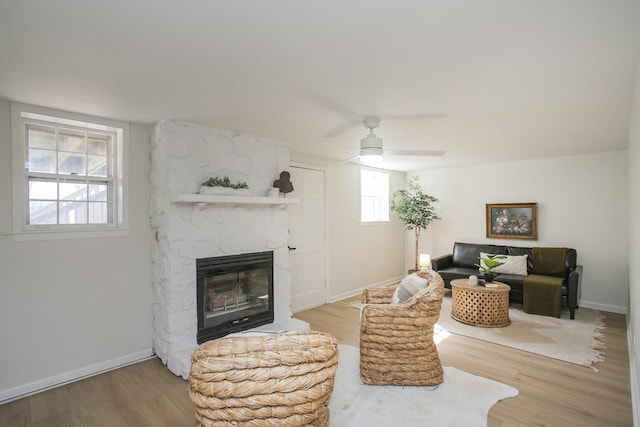 living room with baseboards, wood finished floors, and a stone fireplace