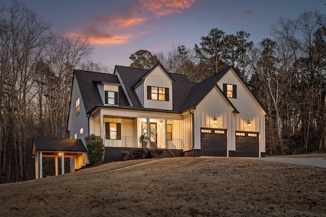 modern inspired farmhouse with a shingled roof, covered porch, board and batten siding, a garage, and driveway