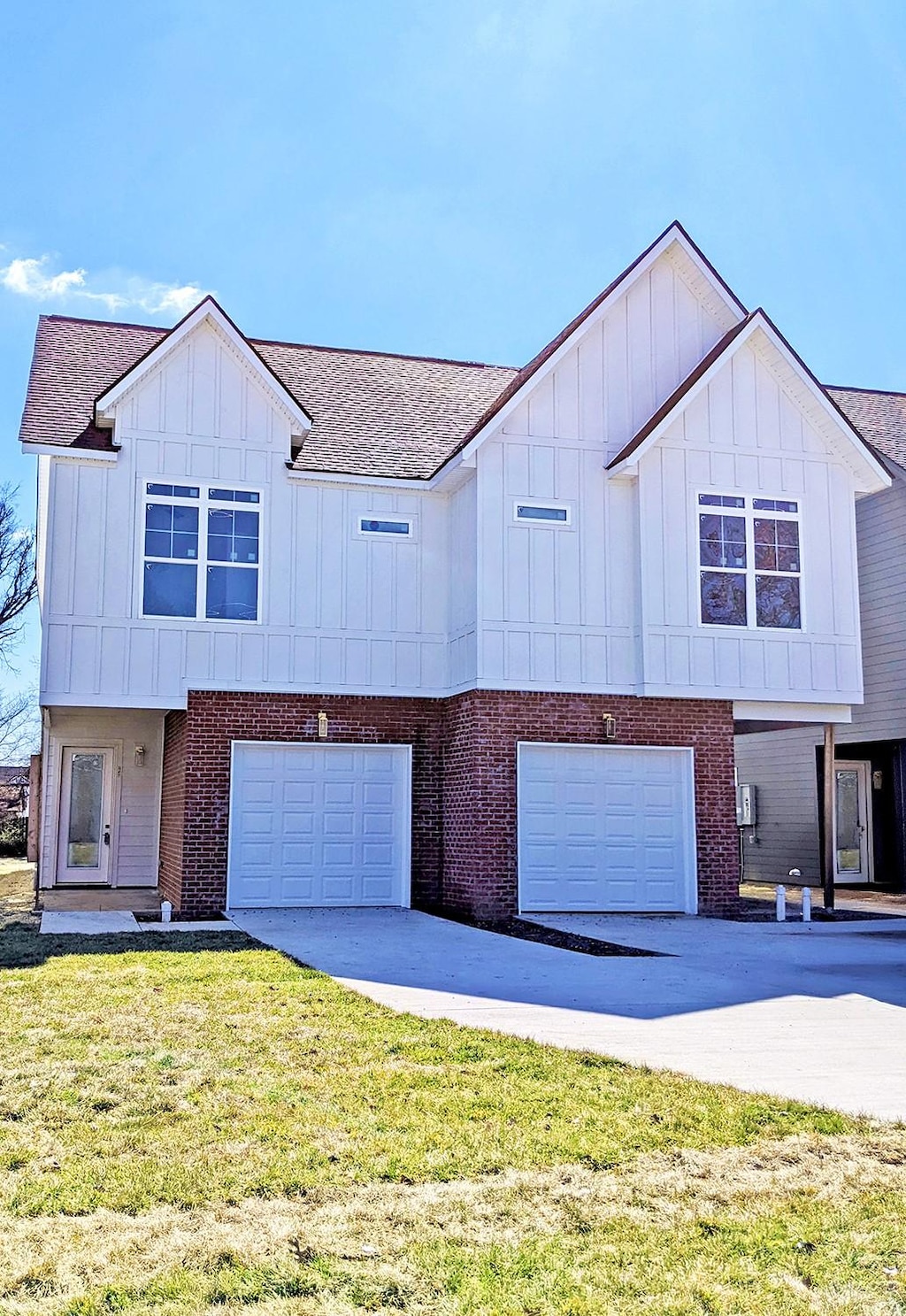 view of front of property with board and batten siding, a front yard, concrete driveway, and an attached garage