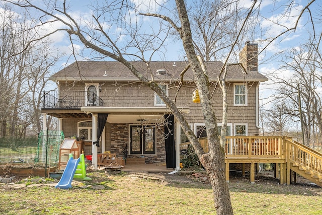 rear view of property featuring a fire pit, a lawn, a chimney, stairway, and a deck