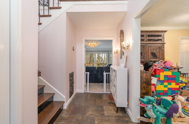 entrance foyer featuring a textured ceiling, baseboards, stairway, stone finish flooring, and crown molding