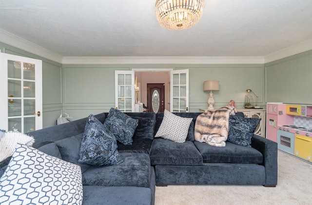 living area with carpet, crown molding, french doors, a chandelier, and a decorative wall