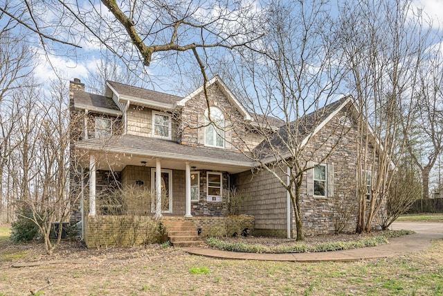 view of front of house featuring a porch, stone siding, and a chimney