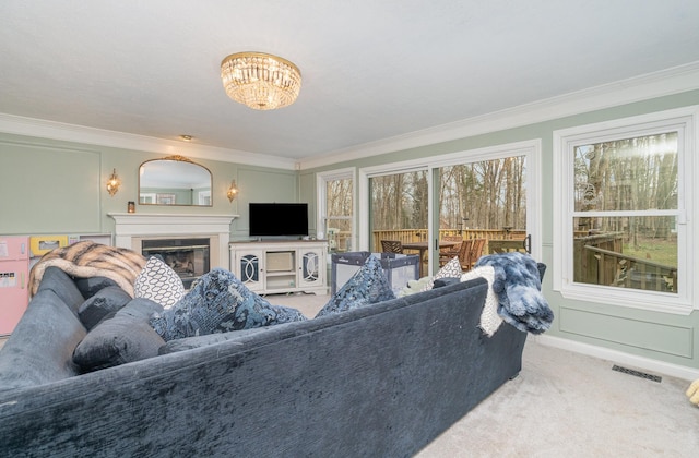 living area featuring visible vents, baseboards, a glass covered fireplace, ornamental molding, and carpet