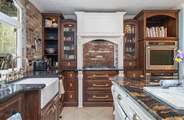 kitchen with stainless steel gas cooktop, a textured ceiling, dark stone counters, and crown molding