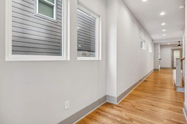 hall featuring light wood-type flooring, baseboards, and recessed lighting