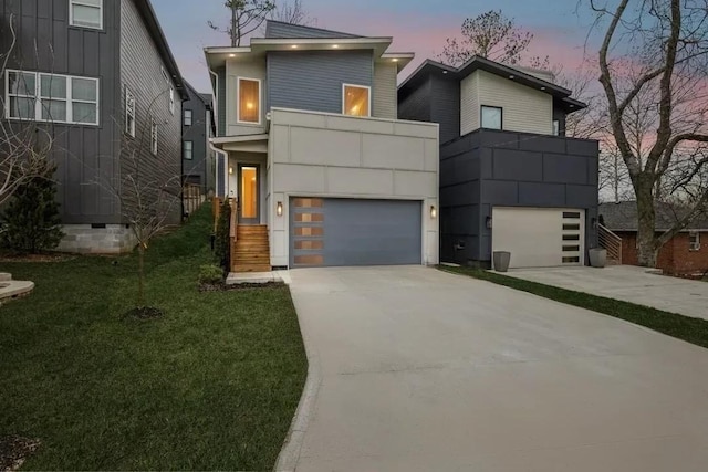 contemporary house featuring a garage, driveway, a balcony, and a lawn