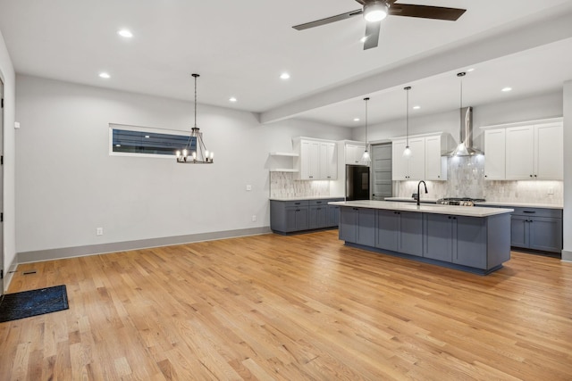 kitchen with refrigerator, open shelves, light countertops, gray cabinets, and wall chimney exhaust hood