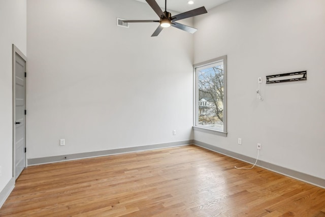 empty room featuring ceiling fan, recessed lighting, a high ceiling, baseboards, and light wood finished floors