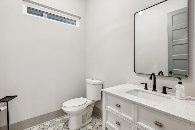 bathroom with baseboards, vanity, and toilet