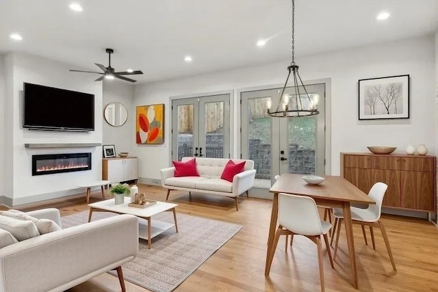 living room featuring french doors, recessed lighting, light wood-style flooring, a glass covered fireplace, and baseboards