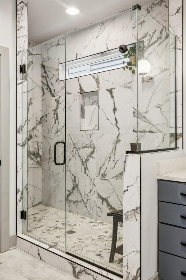 bathroom featuring marble finish floor, a marble finish shower, and vanity