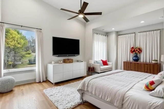 bedroom with lofted ceiling, light wood finished floors, ceiling fan, and multiple windows