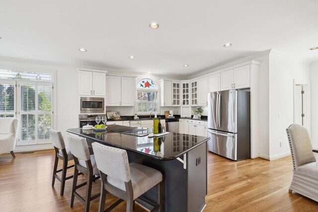 kitchen with light wood finished floors, white cabinets, stainless steel appliances, and a healthy amount of sunlight