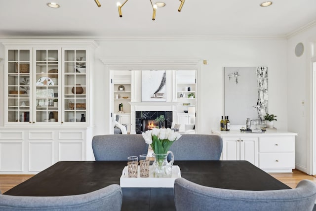 dining room featuring recessed lighting, a premium fireplace, light wood-style floors, and crown molding