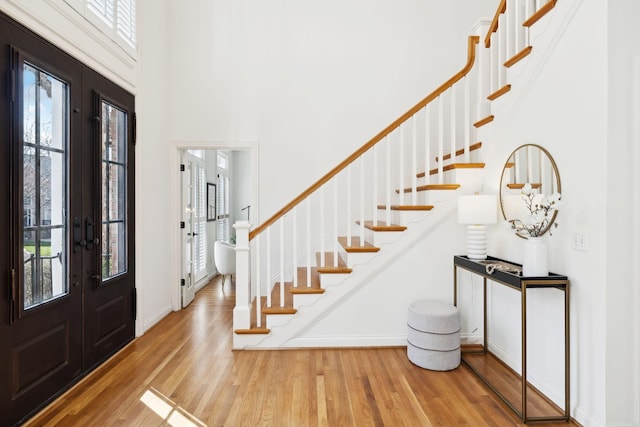 foyer featuring a wealth of natural light, french doors, wood finished floors, and stairway