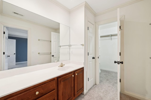 bathroom featuring visible vents, ornamental molding, vanity, baseboards, and a spacious closet