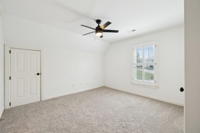carpeted empty room with lofted ceiling, a ceiling fan, baseboards, and visible vents
