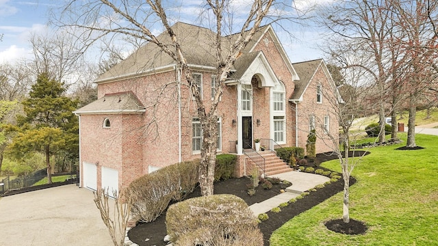 view of front facade with a front yard, an attached garage, brick siding, and driveway