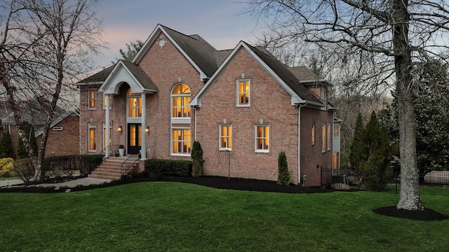 view of front facade with cooling unit, brick siding, and a front lawn