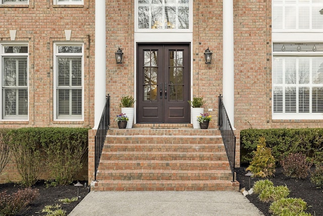 view of exterior entry featuring brick siding and french doors