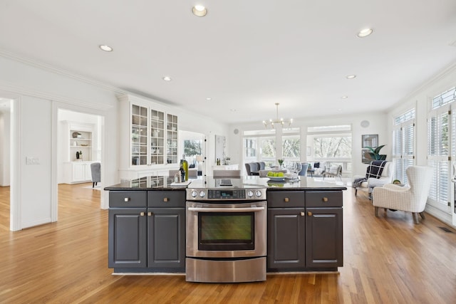 kitchen with crown molding, a notable chandelier, stainless steel electric stove, and a healthy amount of sunlight