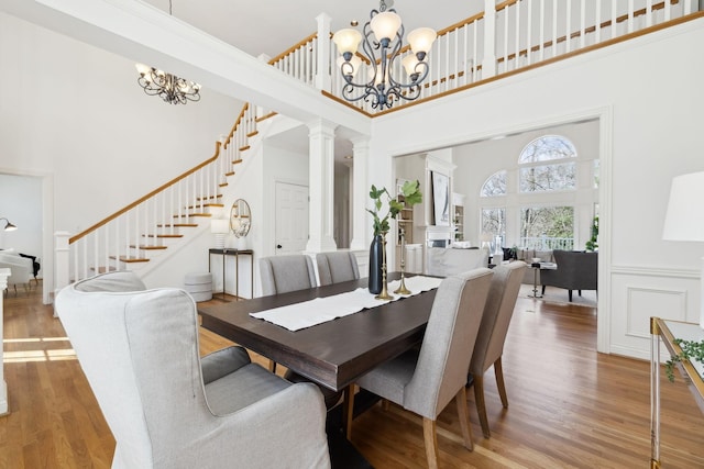 dining room featuring stairway, a high ceiling, an inviting chandelier, and wood finished floors