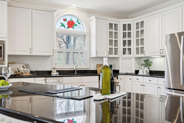 kitchen with dark stone countertops, stainless steel appliances, glass insert cabinets, and white cabinetry