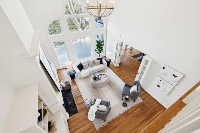 living area featuring wood finished floors, a notable chandelier, a healthy amount of sunlight, and a towering ceiling