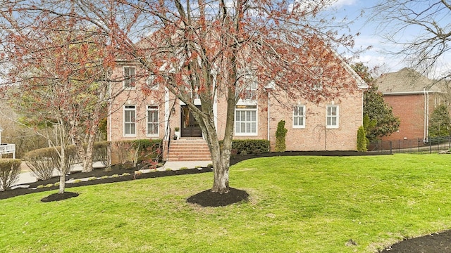 obstructed view of property with a front yard, fence, and brick siding