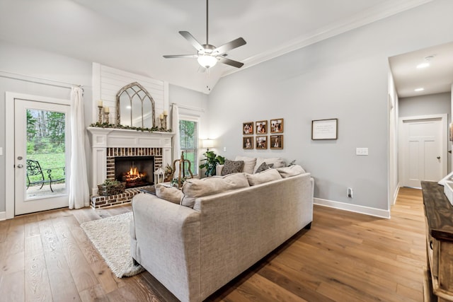 living room with a brick fireplace, plenty of natural light, baseboards, and hardwood / wood-style flooring