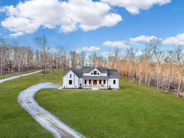 rear view of property featuring covered porch, driveway, a yard, and roof with shingles