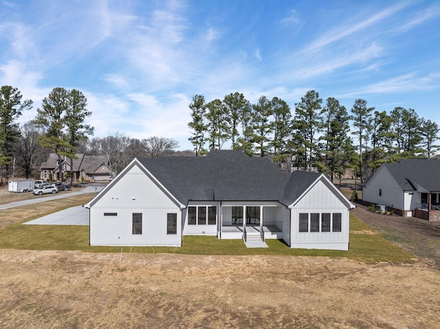 rear view of house with a shingled roof, a yard, and board and batten siding