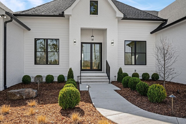 view of front of house with entry steps, brick siding, and a shingled roof