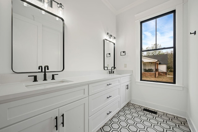 full bath featuring baseboards, double vanity, a sink, and crown molding