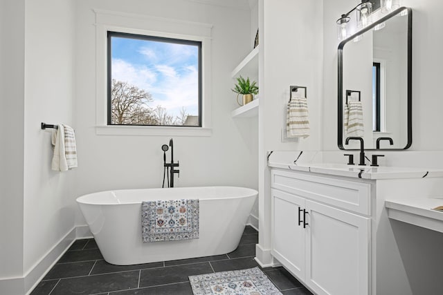 full bath with a freestanding bath, tile patterned flooring, vanity, and baseboards