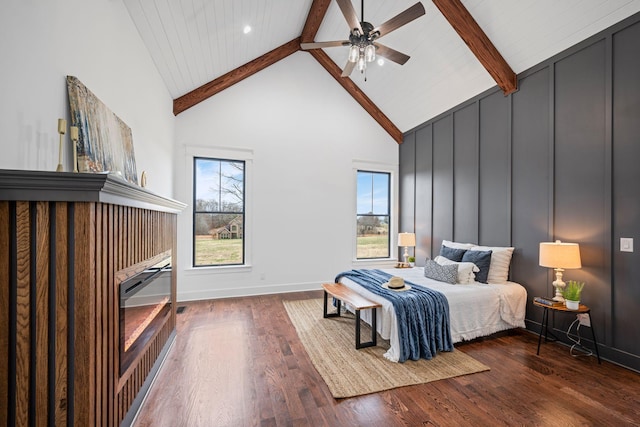 bedroom with high vaulted ceiling, beamed ceiling, wood finished floors, and a decorative wall