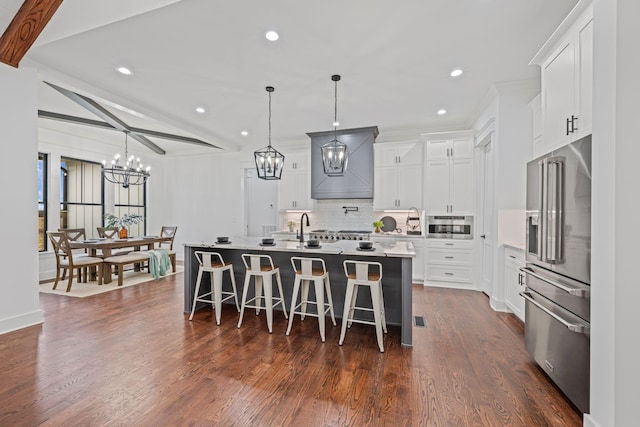 kitchen with light countertops, appliances with stainless steel finishes, beam ceiling, tasteful backsplash, and an inviting chandelier