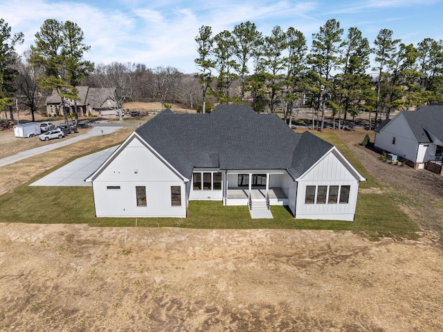 rear view of property with a yard, board and batten siding, and roof with shingles