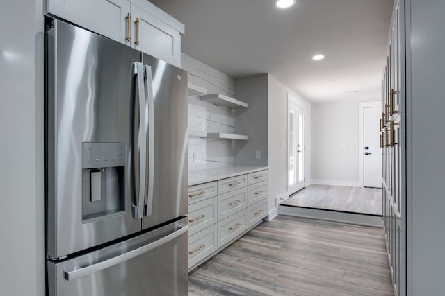 kitchen with baseboards, light wood-style flooring, stainless steel refrigerator with ice dispenser, open shelves, and recessed lighting