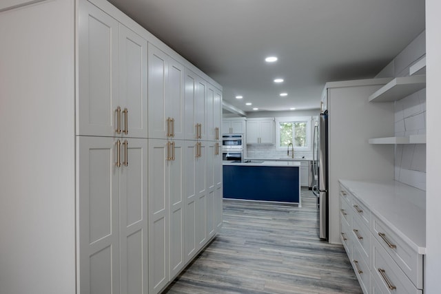 kitchen featuring a kitchen island, stainless steel appliances, light countertops, open shelves, and recessed lighting