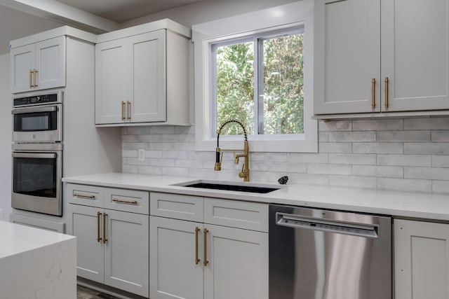 kitchen featuring appliances with stainless steel finishes, a sink, a wealth of natural light, and tasteful backsplash