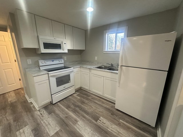 kitchen with white appliances, a sink, white cabinets, light countertops, and dark wood-style floors